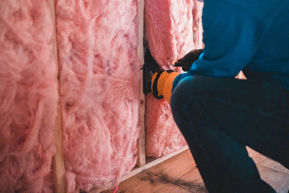 Fiberglass batt insulation being fitted between wall studs