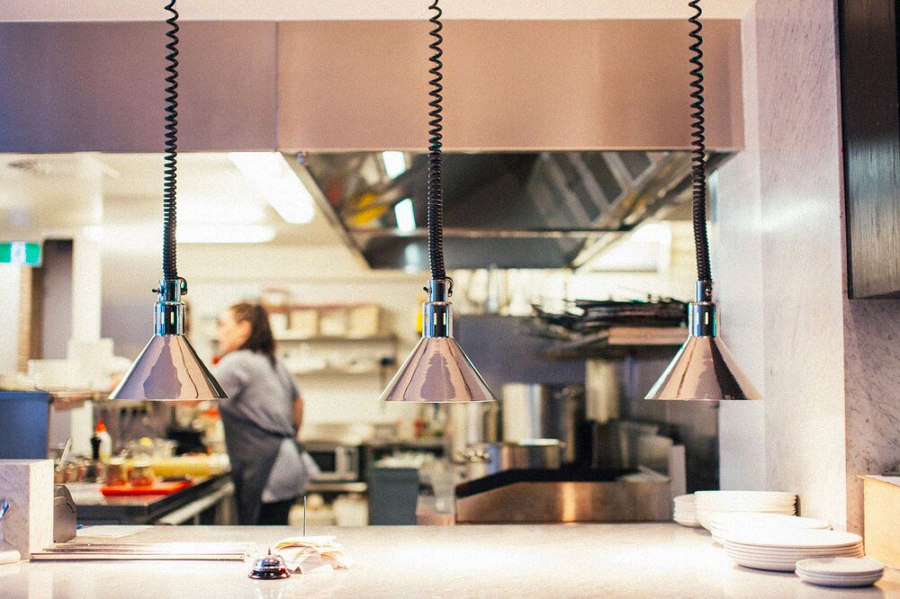 A stainless steel commercial kitchen line under service lamps
